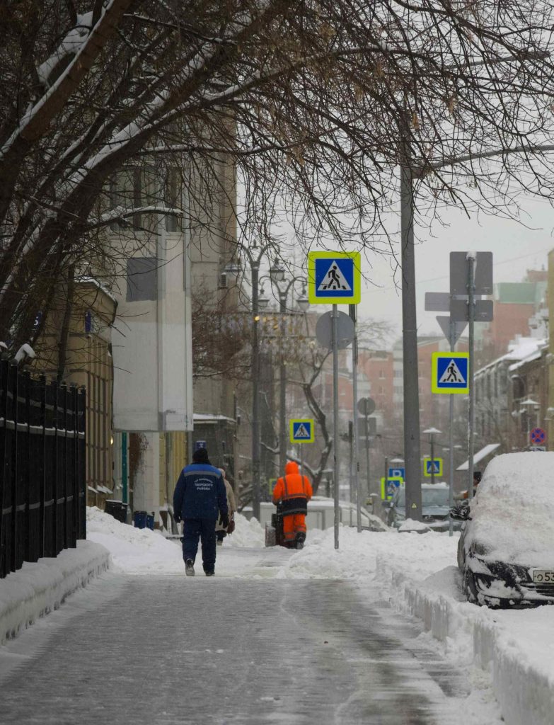 Ein Mann geht eine schneebedeckte Straße entlang.